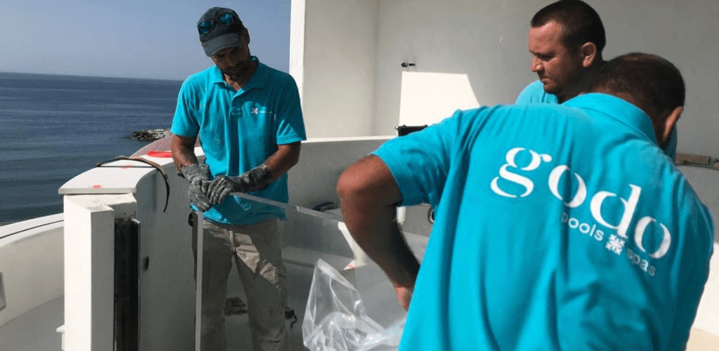 GodoPools team placing acrylic panel in a pool